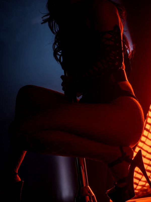 silhouette of sexy stripper pole dancing on blue with red lighting